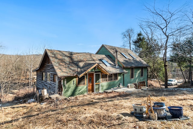 rustic home with a garage and a shingled roof