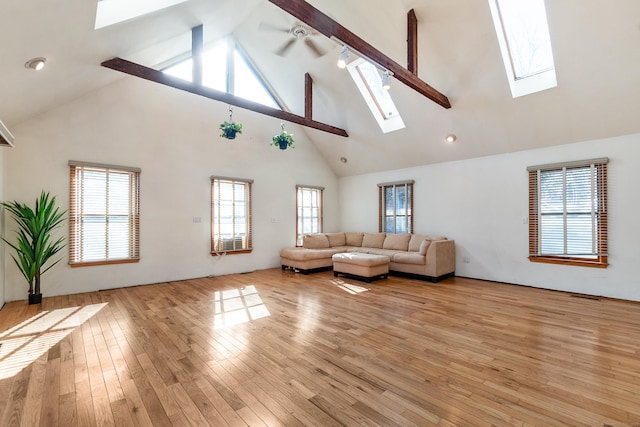 unfurnished living room featuring ceiling fan, light wood finished floors, visible vents, and a wealth of natural light