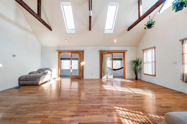 unfurnished living room featuring light wood-style flooring, a high ceiling, a skylight, and a wealth of natural light