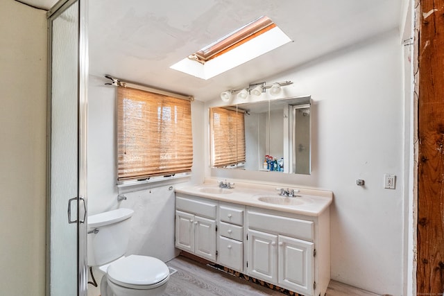 full bath with double vanity, lofted ceiling with skylight, toilet, and a sink