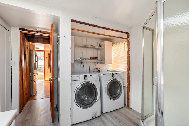 laundry room with laundry area, washer and clothes dryer, light wood-type flooring, and a wealth of natural light