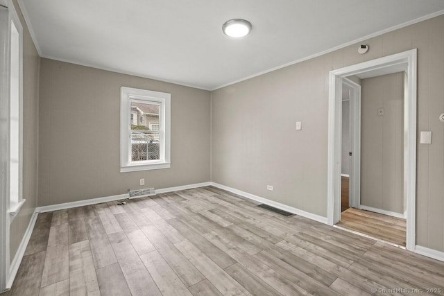 unfurnished room with wood finished floors, visible vents, and crown molding