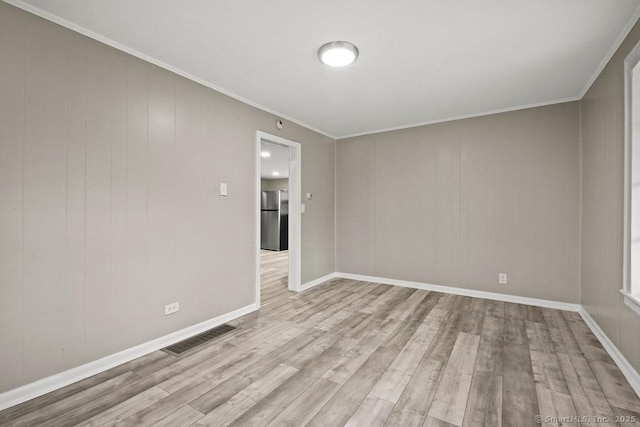 spare room with ornamental molding, visible vents, baseboards, and wood finished floors