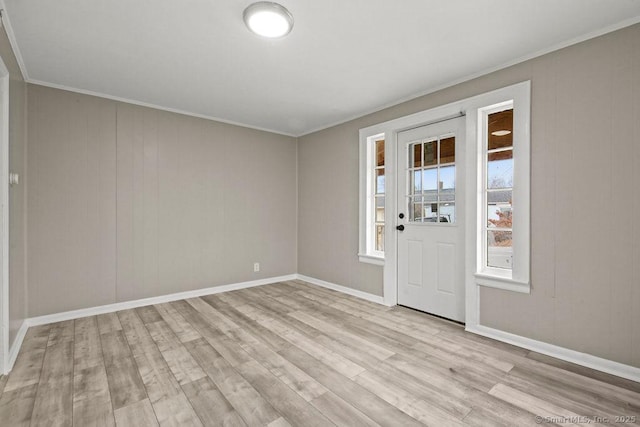 interior space featuring baseboards, crown molding, and light wood finished floors