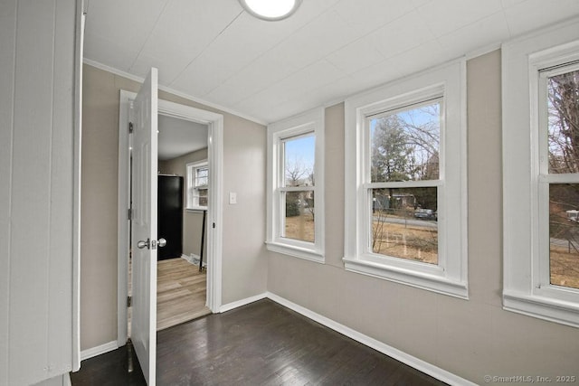 interior space with a healthy amount of sunlight, baseboards, dark wood-style flooring, and ornamental molding