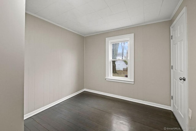 empty room featuring dark wood-type flooring, crown molding, and baseboards