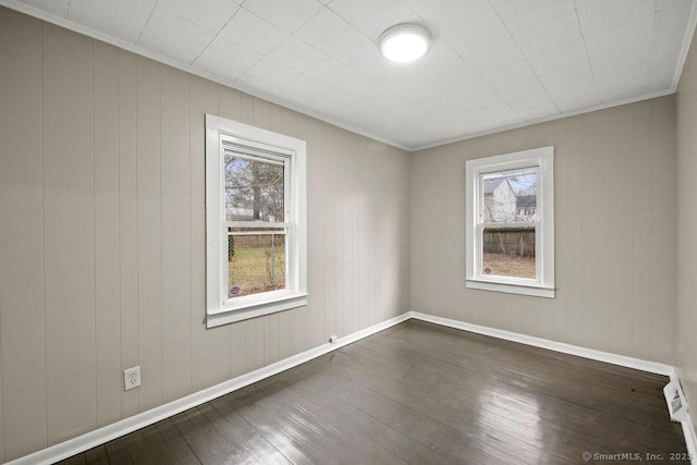 unfurnished room with baseboards, dark wood-type flooring, and a healthy amount of sunlight