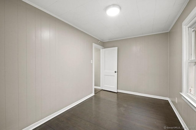 empty room featuring crown molding, baseboards, and dark wood-style flooring