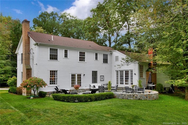 back of property featuring a patio area, a lawn, and a chimney