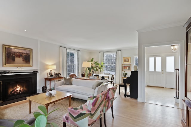 living area featuring a fireplace with flush hearth, light wood-style floors, and ornamental molding