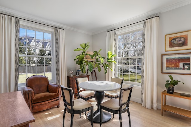 dining space with light wood-type flooring and crown molding