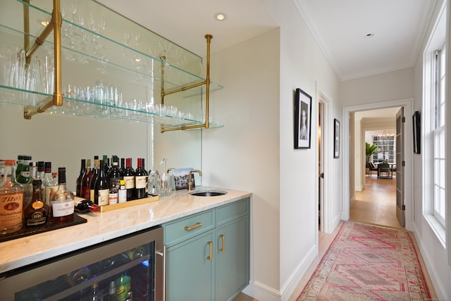 bar with beverage cooler, baseboards, ornamental molding, indoor wet bar, and a sink