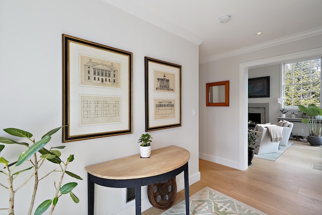 hallway featuring light wood-style flooring, baseboards, and ornamental molding