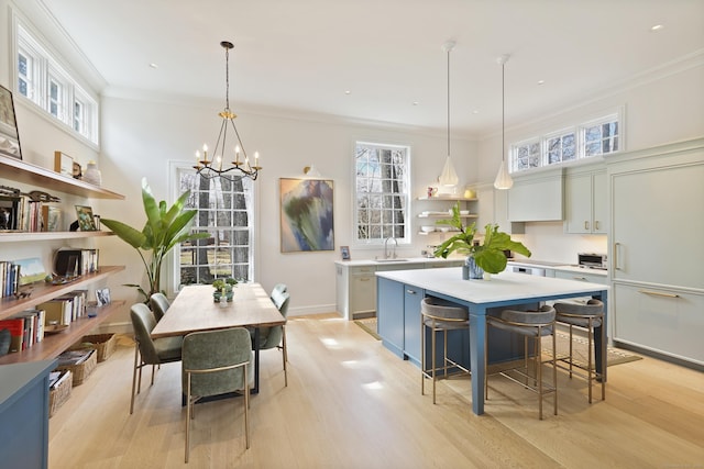 kitchen featuring light wood finished floors, a kitchen island, open shelves, light countertops, and crown molding