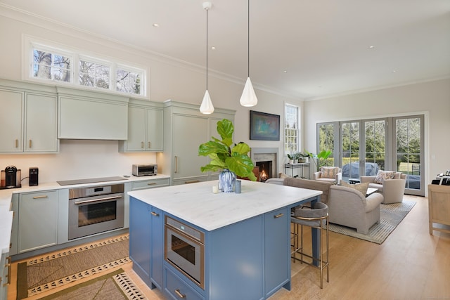 kitchen featuring blue cabinetry, crown molding, a kitchen bar, a lit fireplace, and stainless steel appliances