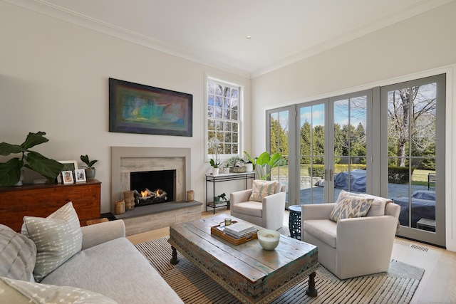 living area with light wood-type flooring, visible vents, ornamental molding, french doors, and a fireplace