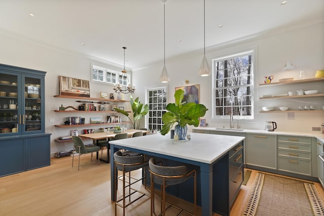 kitchen featuring open shelves, crown molding, light countertops, and a sink