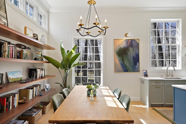 dining space featuring a notable chandelier, light wood-style floors, baseboards, and ornamental molding