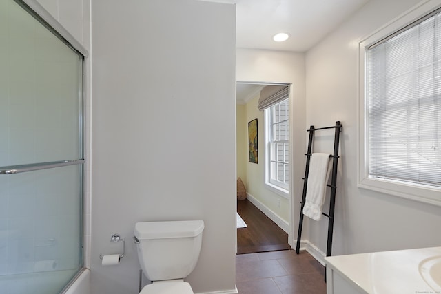 full bathroom featuring vanity, baseboards, shower / bath combination with glass door, tile patterned floors, and toilet