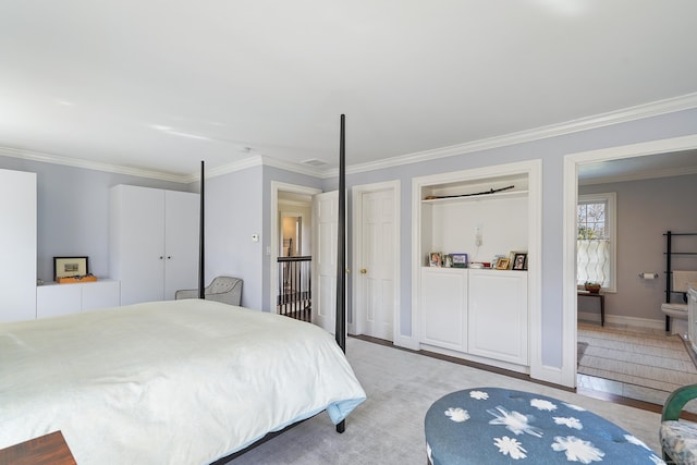 bedroom featuring crown molding, baseboards, two closets, and connected bathroom