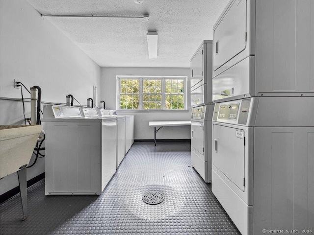 common laundry area with stacked washer / dryer, washer and clothes dryer, and a textured ceiling