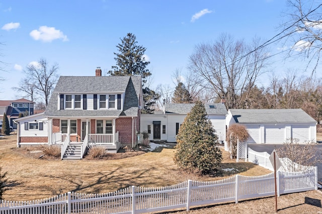 view of front facade with covered porch, a fenced front yard, a chimney, and a garage