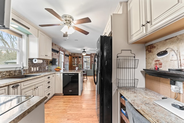 kitchen with light wood-type flooring, black appliances, light countertops, and a sink