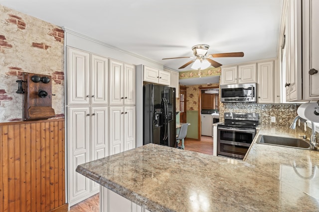 kitchen with decorative backsplash, appliances with stainless steel finishes, a ceiling fan, a sink, and a peninsula