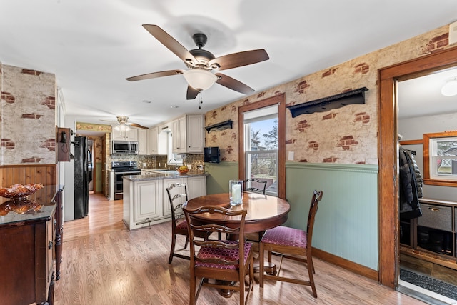 dining area with light wood-type flooring and wainscoting