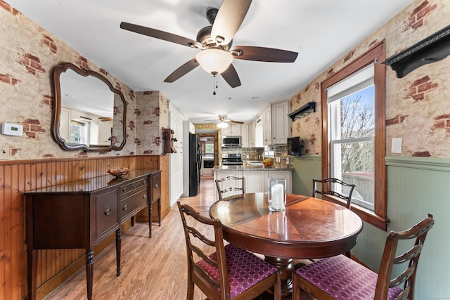 dining room with light wood-style floors and a wainscoted wall