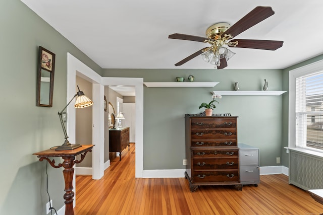 interior space with baseboards, ceiling fan, light wood-type flooring, and radiator