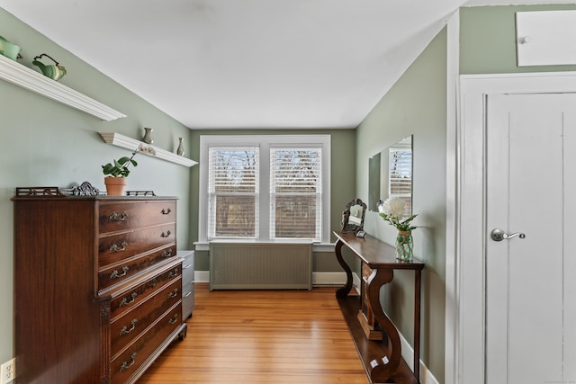 living area featuring light wood-type flooring, radiator, and baseboards