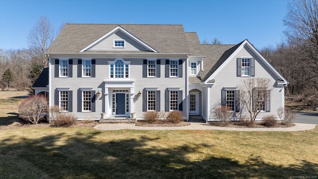 view of front facade featuring roof with shingles and a front lawn