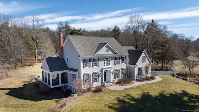 view of front of house featuring a chimney and a front lawn