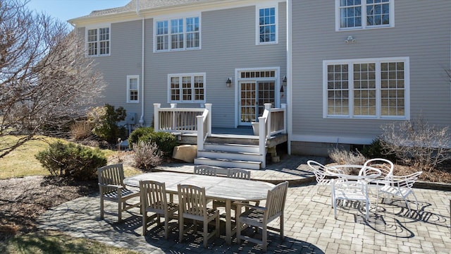 back of house featuring outdoor dining area, a deck, and a patio area