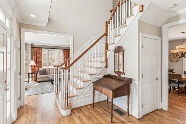 entrance foyer featuring stairway, light wood-style floors, visible vents, and ornamental molding