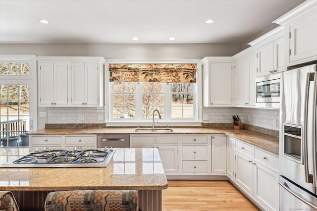 kitchen with a healthy amount of sunlight, stainless steel appliances, light wood-style floors, and a sink