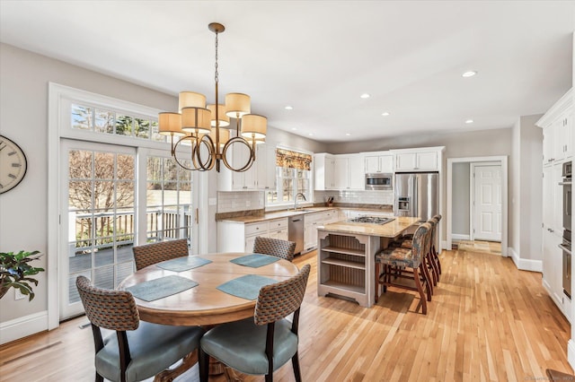 dining area with recessed lighting, baseboards, a notable chandelier, and light wood finished floors