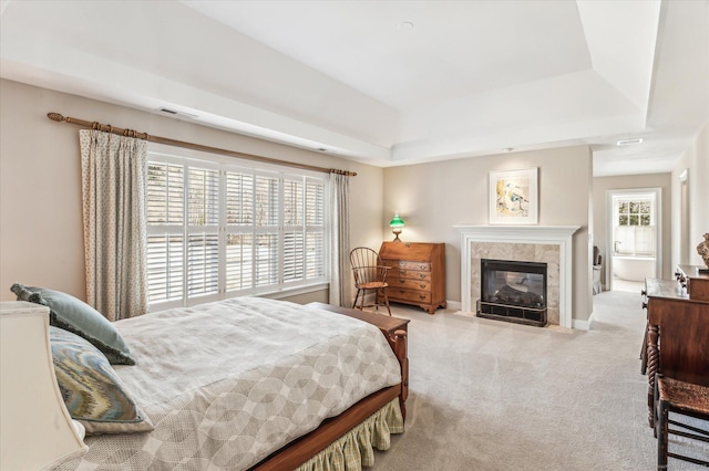 bedroom with a tiled fireplace, visible vents, a tray ceiling, and carpet floors