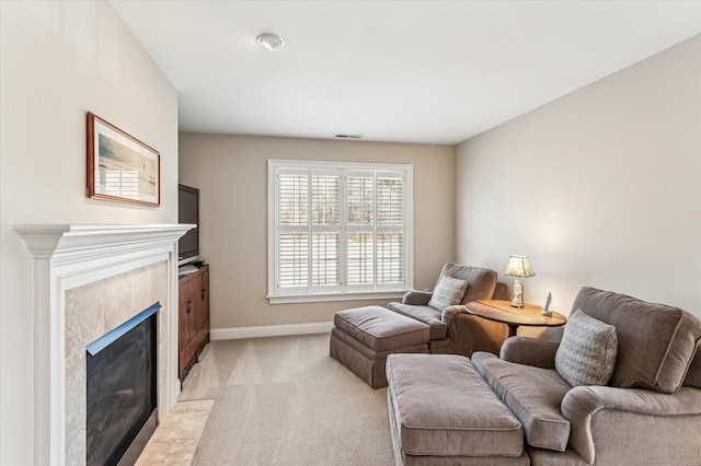 living area with visible vents, baseboards, a high end fireplace, and light carpet