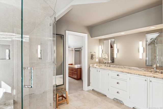 bathroom with a sink, baseboards, a stall shower, and double vanity