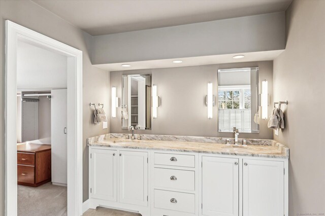 bathroom featuring double vanity, recessed lighting, baseboards, and a sink