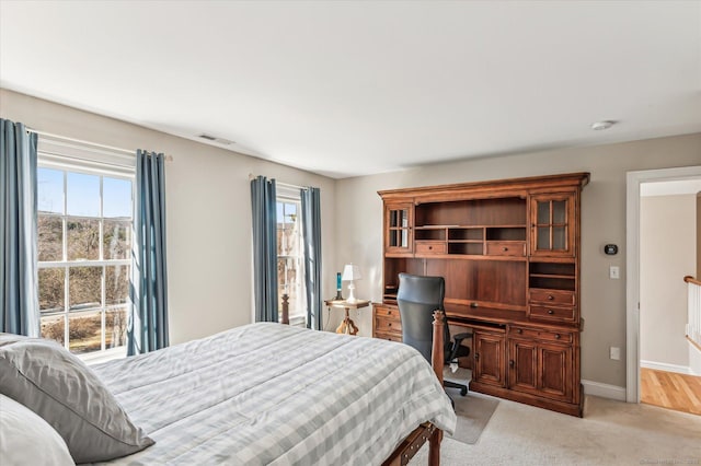 bedroom featuring visible vents, multiple windows, light colored carpet, and baseboards