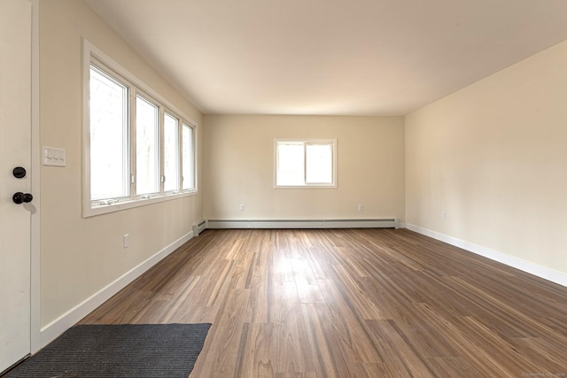 empty room featuring baseboard heating, baseboards, and wood finished floors