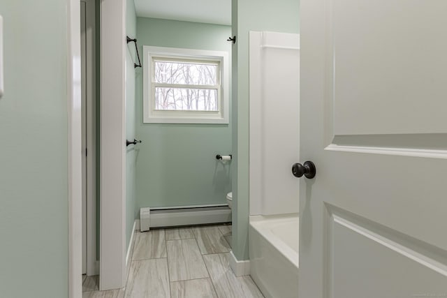 full bathroom with a washtub, baseboard heating, and toilet