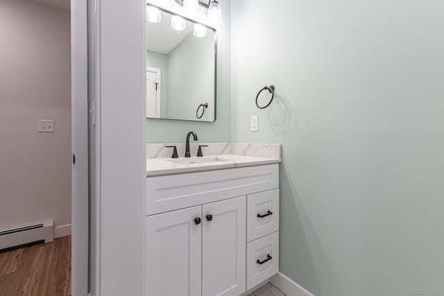 bathroom with wood finished floors, vanity, baseboards, and a baseboard radiator