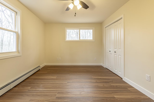 unfurnished bedroom featuring a closet, wood finished floors, baseboards, and a baseboard radiator