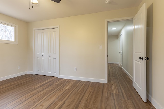 unfurnished bedroom with baseboards, dark wood-style flooring, a closet, and ceiling fan