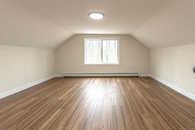 bonus room with a baseboard heating unit, baseboards, dark wood-style flooring, and vaulted ceiling