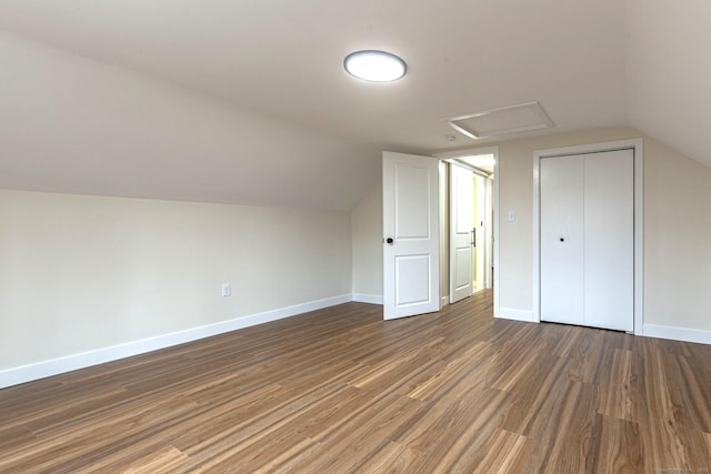 additional living space featuring lofted ceiling, attic access, wood finished floors, and baseboards